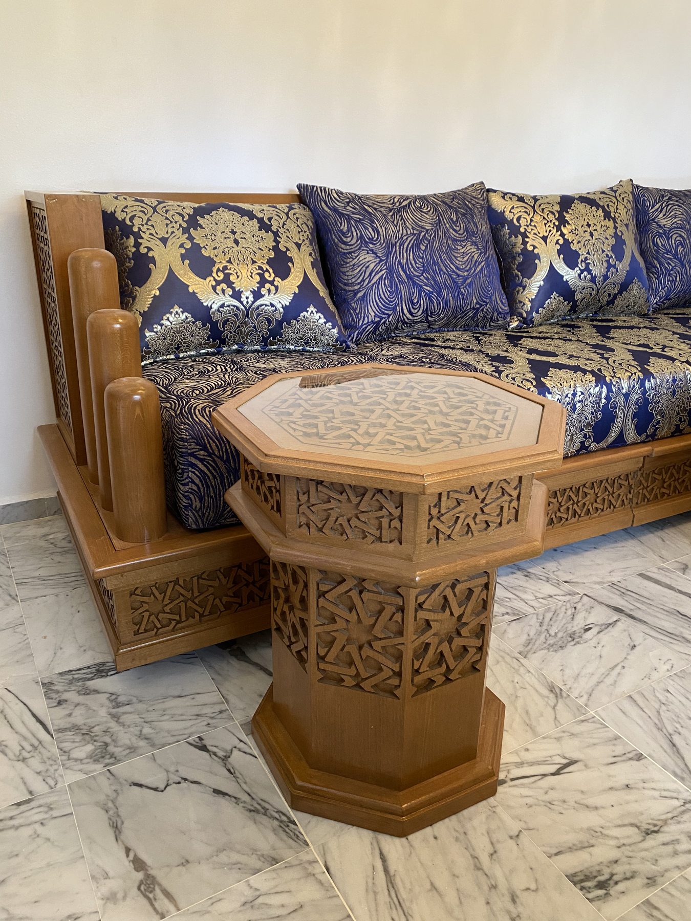Table octogonale sculptée devant une banquette bleue