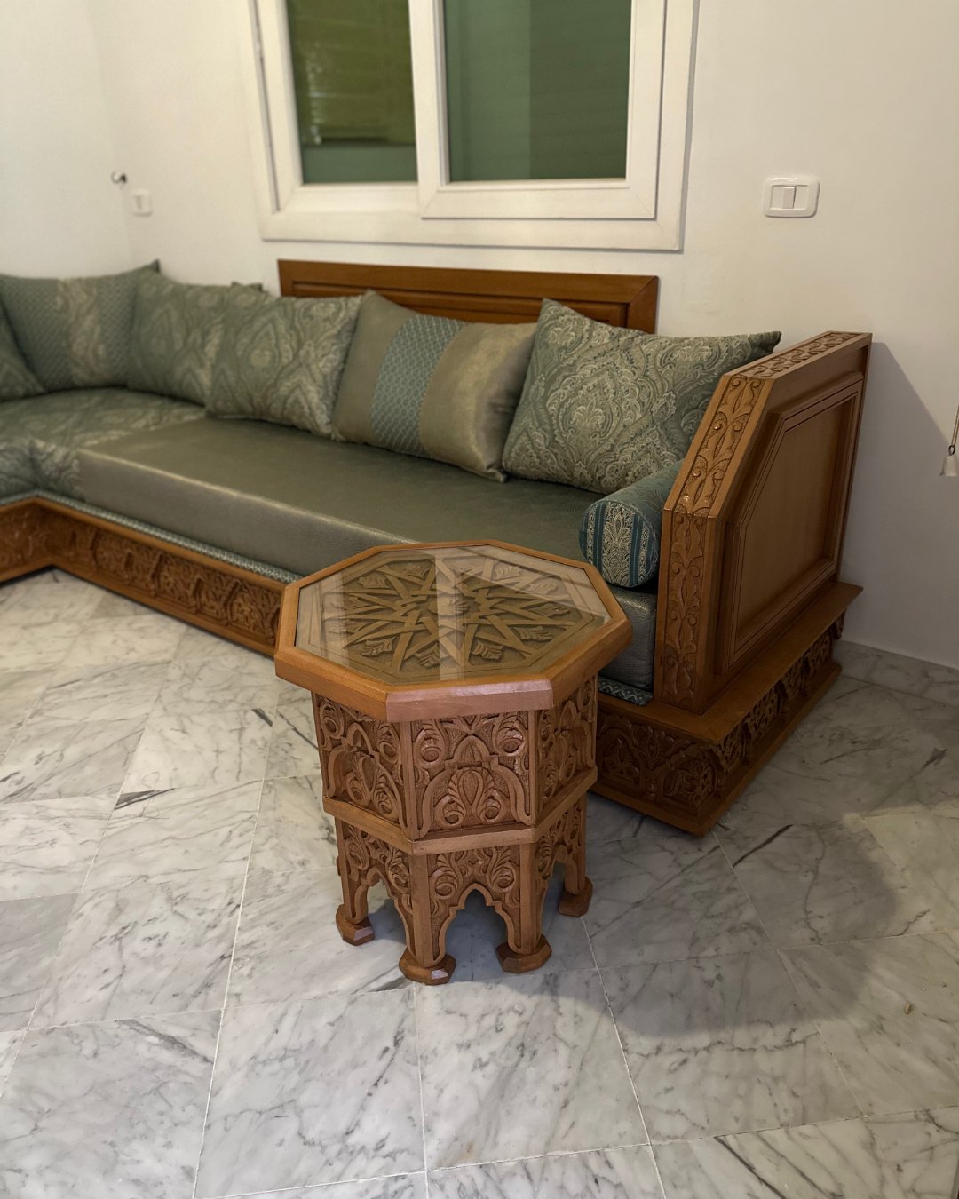 Détail de la banquette verte et de sa table sculptée